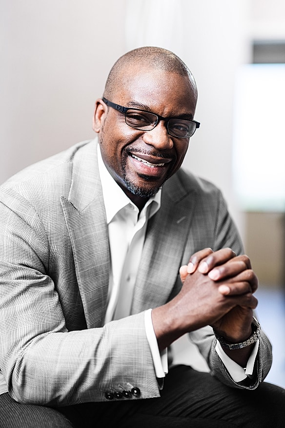 Smiling man in a gray suit and glasses.