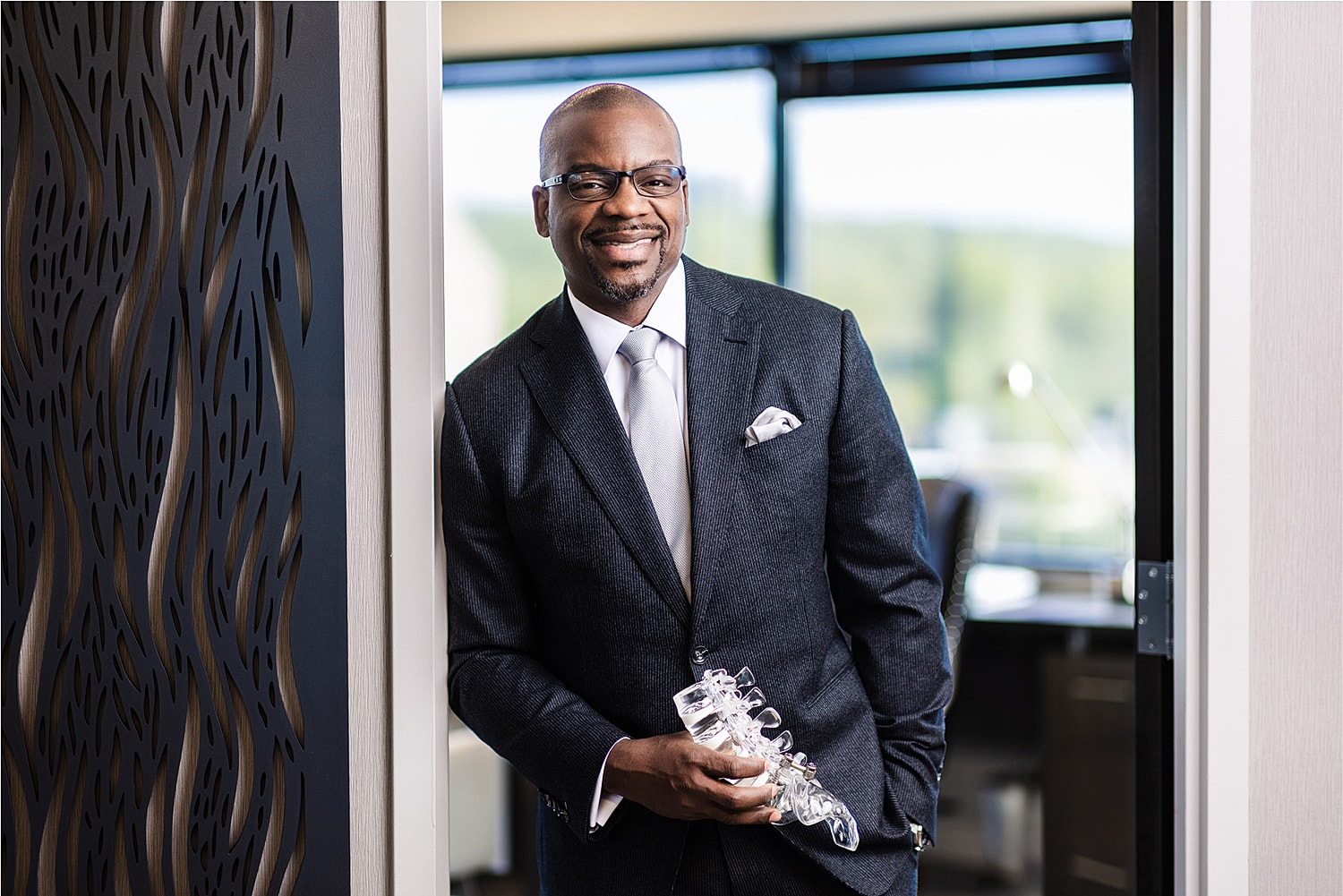Smiling man in suit holding a glass trophy.