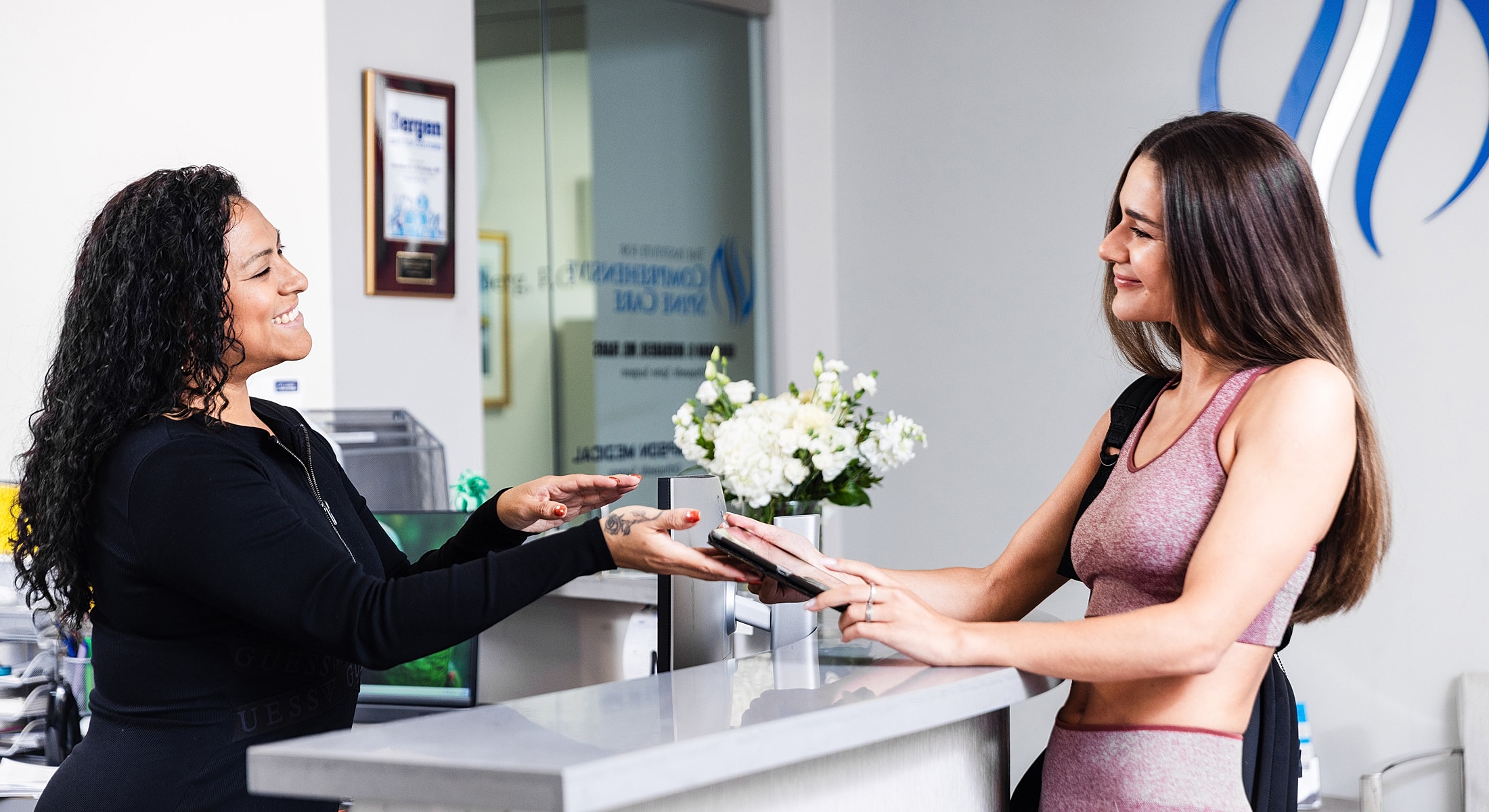Receptionist assisting an endoscopic lumbar discectomy patient at a front desk.